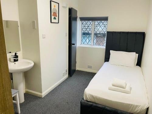 a small bedroom with a bed and a sink at Woodford Hotel in London