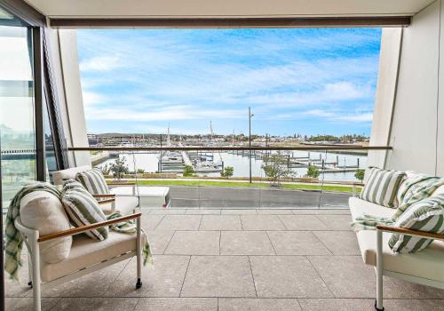 a balcony with two chairs and a view of the water at Marinafront Retreat Shell Cove in Shellharbour