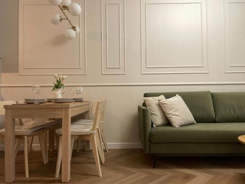 Una sala de estar con un sofá verde y una mesa. en Apartamenty Premium Przy Plaży Morzlive, en Ustronie Morskie