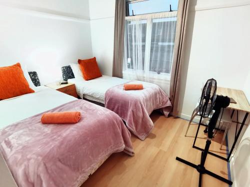 a room with two beds with pink sheets and a window at Regent Residential House in Whangarei