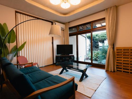 a living room with a blue couch and a glass table at Izumi Tei 泉邸100m2 旅館風一軒家 family friendly villa in Kitakyushu