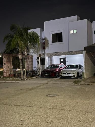 two cars parked in a parking lot in front of a house at Casa completa y equipada 4 habitaciones 6 camas asador y juguetes para niños A 10 minutos de parques industriales, clínicas 71 y 16 del IMSS y del ISSSTE juegos Arcade in Torreón