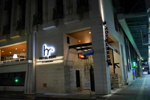 a building with a neon sign on the side of it at Hotel Resh Tottori Ekimae in Tottori