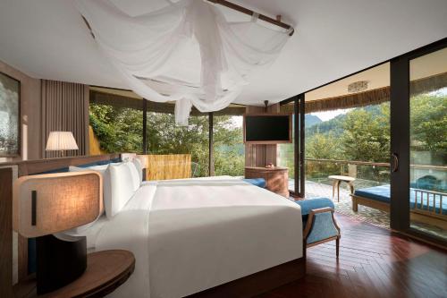 a bedroom with a large white bed and a large window at Garrya Mù Cang Chải in Mù Cang Chải