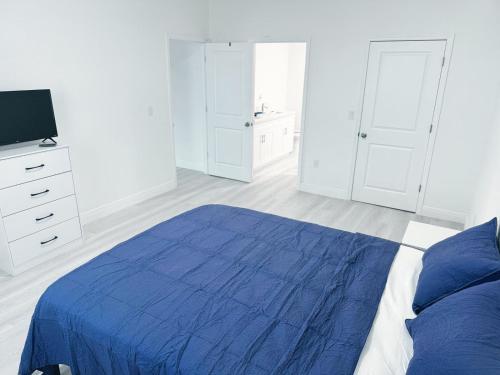 una camera bianca con un letto blu e una TV di Casa compartida vacacional a La Belle