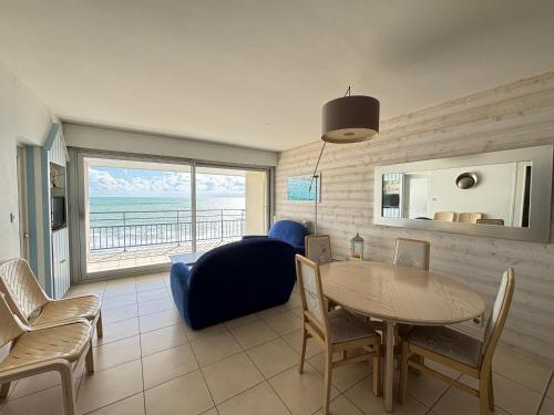 un salon avec une table et un canapé bleu dans l'établissement Appartement face plage au 9ème étage avec garage privatif - FR-1-197-622, à Les Sables-dʼOlonne