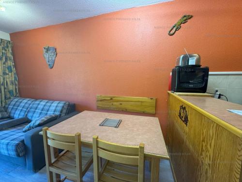 Cette chambre dispose d'une table, d'une télévision et d'un canapé. dans l'établissement Appartement F2 au pied des pistes - 5 couchages avec Wi-Fi et parking - FR-1-295-206, aux Angles