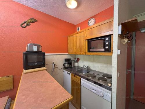 - une cuisine avec des murs orange, un évier et un four micro-ondes dans l'établissement Appartement F2 au pied des pistes - 5 couchages avec Wi-Fi et parking - FR-1-295-206, aux Angles