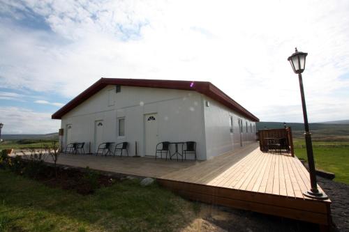 a large white building with chairs on a wooden deck at Guesthouse Storu-Laugar in Laugar