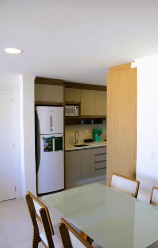 a kitchen with a table and a white refrigerator at Apto de duas suítes com vista mar - 100 metros da praia em Canasvieiras in Florianópolis