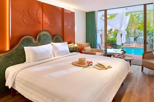 a bedroom with a large bed with a book on it at Burasari Phuket Resort & Spa in Patong Beach