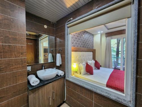 a bathroom with a bed and a sink and a mirror at The Cedar Vatika Hotel and Restaurant in Dharamshala