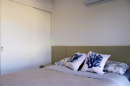 a bedroom with a bed with blue and white pillows at Apto de duas suítes com vista mar - 100 metros da praia em Canasvieiras in Florianópolis