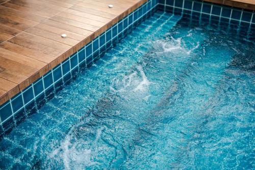 a large swimming pool with a blue tiled floor at Hua Hin Pool Villa and Pool table with 3 bedrooms, 3 bathrooms near Cha-Am beach in Nikhom Sang Ton Eng Khuan Phet