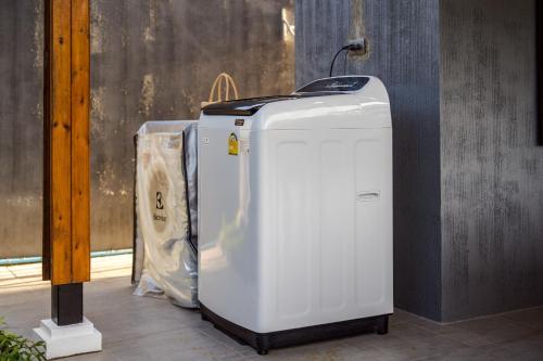 a white refrigerator sitting next to a wall at Hua Hin Pool Villa and Pool table with 3 bedrooms, 3 bathrooms near Cha-Am beach in Nikhom Sang Ton Eng Khuan Phet