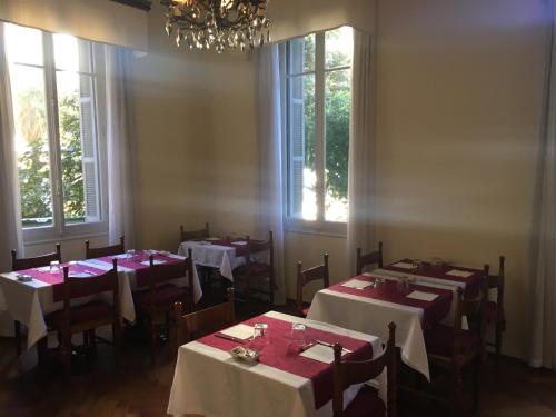 ein Esszimmer mit Tischen, Stühlen und Fenstern in der Unterkunft Hotel Liberty in Sanremo