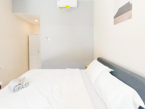 a bedroom with a white bed with two slippers on it at The TAMU HOUSE Syariah Solo RedPartner in Bonorejo