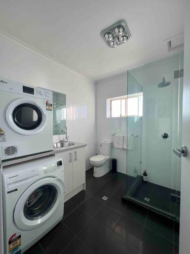 a bathroom with a washing machine and a toilet at Beach apartment 22 esplanade sea-views in Glenelg