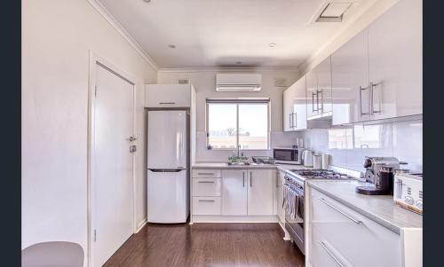 グレネルグにあるBeach apartment 22 esplanade sea-viewsのキッチン(白い家電製品、白い冷蔵庫付)