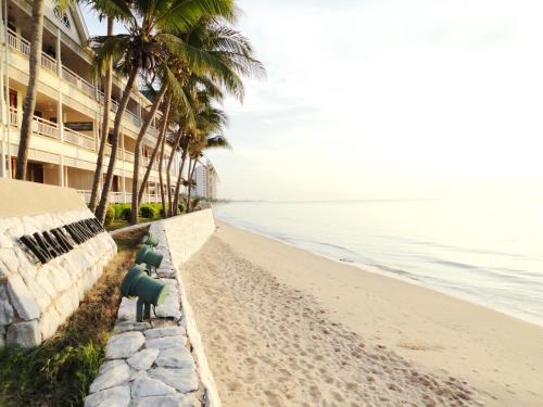 a beach with palm trees next to a building at บ้านมนชเลชะอำ ติดชายหาด Baan Monchale in Ban Sa