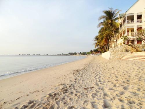 a beach with palm trees and a building at บ้านมนชเลชะอำ ติดชายหาด Baan Monchale in Ban Sa