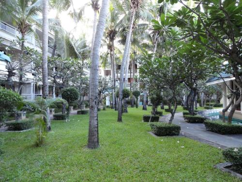 a park with palm trees in front of a building at บ้านมนชเลชะอำ ติดชายหาด Baan Monchale in Ban Sa