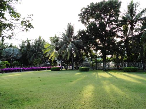 a park with palm trees and a large grass field at บ้านมนชเลชะอำ ติดชายหาด Baan Monchale in Ban Sa