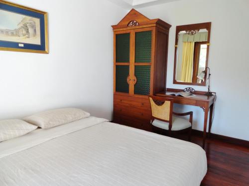 a bedroom with a bed and a desk and a mirror at บ้านมนชเลชะอำ ติดชายหาด Baan Monchale in Ban Sa