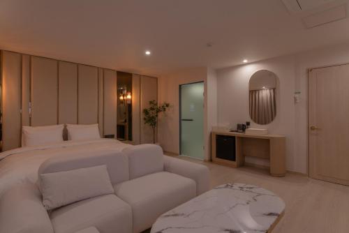a bedroom with a white bed and a couch at Vibe Hotel Gimhae Jangyu in Gimhae
