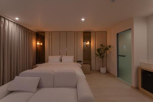 a bedroom with a large white bed and a couch at Vibe Hotel Gimhae Jangyu in Gimhae