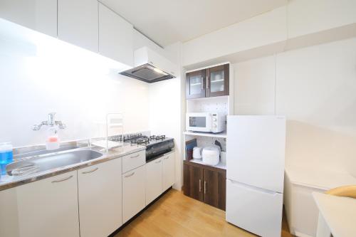 a white kitchen with a sink and a refrigerator at ノーザンヒルズ南6条 in Sapporo