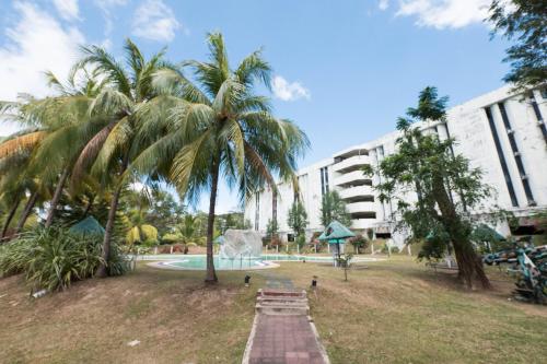 a park with a palm tree in front of a building at RAINFOREST Nest Self-Service Home in Subic Bay - Monkeys, Bats, Roofdeck! in Subic Bay Intl