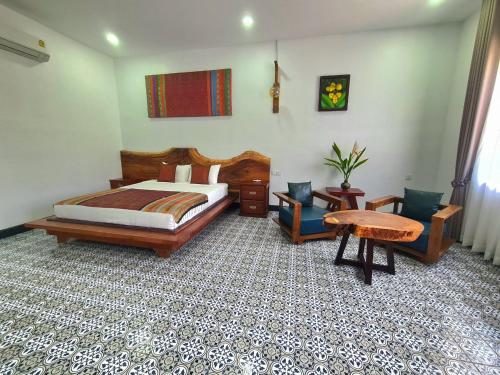 a bedroom with a bed and a table and chairs at Villa Romduol in Kampot