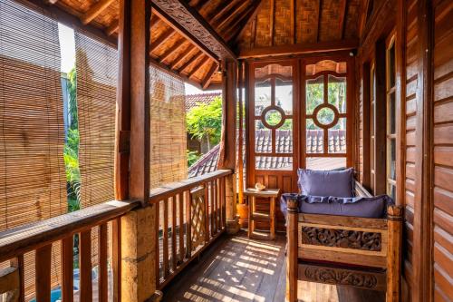 a porch of a wooden house with a bench at Carmen Kayu villa Lombok in Montongbuwoh