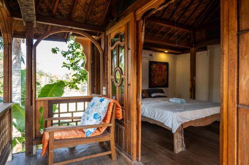 a bedroom with a bed and a chair in a room at Carmen Kayu villa Lombok in Montongbuwoh