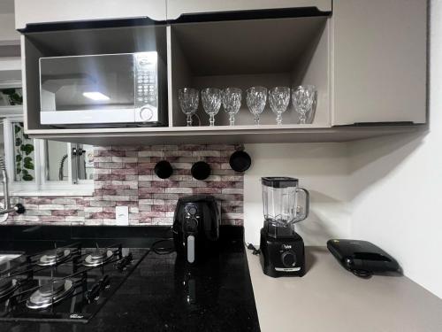 a kitchen with a counter with a blender and a microwave at Apartamento em Frente ao Shopping Itaguaçu in São José