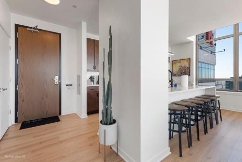 a kitchen and living room with a counter and stools at K2 Sky High Apartments with Stunning Chicago Views in West Loop in Chicago