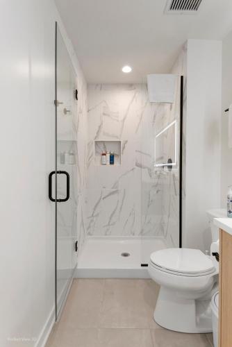 a white bathroom with a shower and a toilet at K2 Sky High Apartments with Stunning Chicago Views in West Loop in Chicago