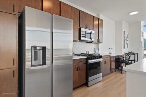 a stainless steel refrigerator in a kitchen with wooden cabinets at K2 Sky High Apartments with Stunning Chicago Views in West Loop in Chicago