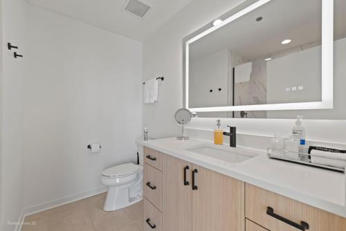 a bathroom with a sink and a toilet and a mirror at K2 Sky High Apartments with Stunning Chicago Views in West Loop in Chicago