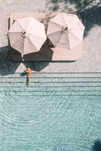a man standing next to a pool of water with umbrellas at Centara Karon Resort Phuket in Karon Beach