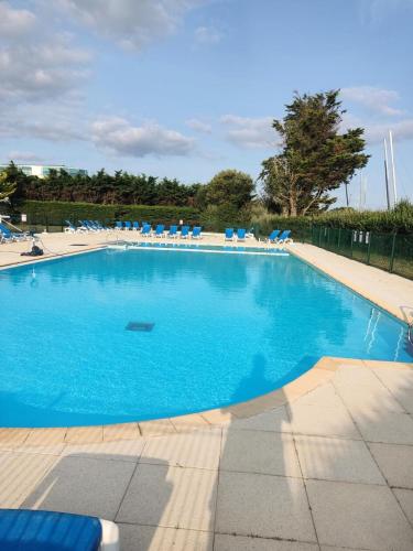 une grande piscine bleue avec des chaises longues bleues dans l'établissement Résidence Port du Crouesty - maeva Home - Appartement 2 pièces 5 personnes - Confort MAE-2142, à Arzon