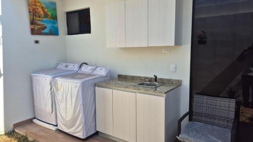 a kitchen with a sink and a washing machine at A good rest upon arrival or departure from your trip just 7 minutes from El Salvador's airport in Las Flores