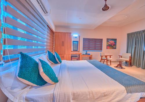 a bedroom with a large bed with blue pillows at Beachside Pool Villa - Karthiyayini by VOYE HOMES in Turavūr
