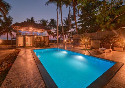 a large blue swimming pool in front of a house at Beachside Pool Villa - Karthiyayini by VOYE HOMES in Turavūr