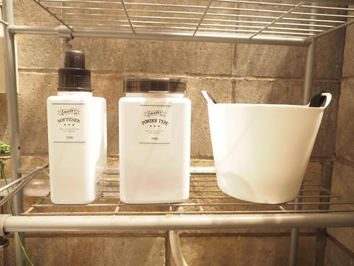 three bottles and a bucket on a shelf at 御宿ゲストハウス 海おやぶん in Onjuku