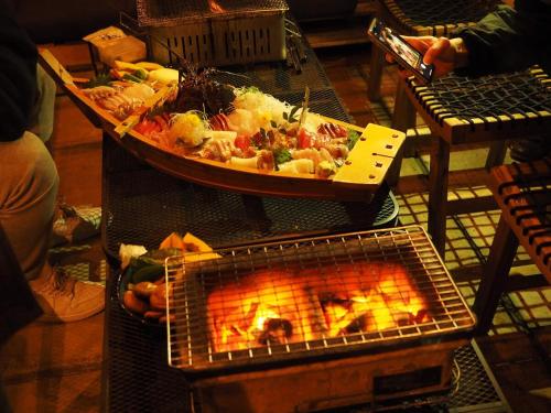a plate of food is cooking over a fire at 御宿ゲストハウス 海おやぶん in Onjuku