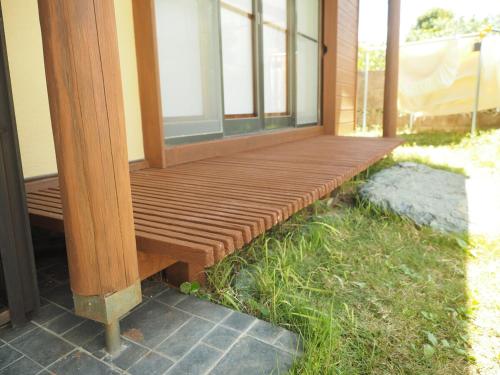 a porch with a wooden bench on the side of a house at 御宿ゲストハウス 海おやぶん in Onjuku