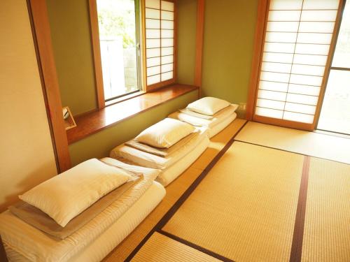 a row of beds in a room with windows at 御宿ゲストハウス 海おやぶん in Onjuku
