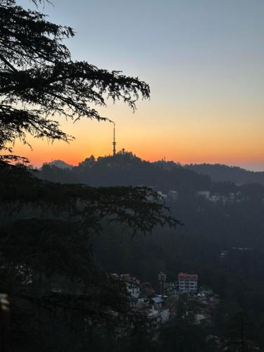 a sunset with a tower on top of a hill at Lords Grey near Mall Road in Shimla